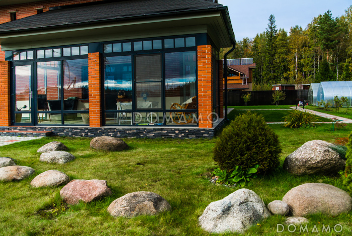 Проект каркасного дома с просторной верандой, гаражом и навесом для авто